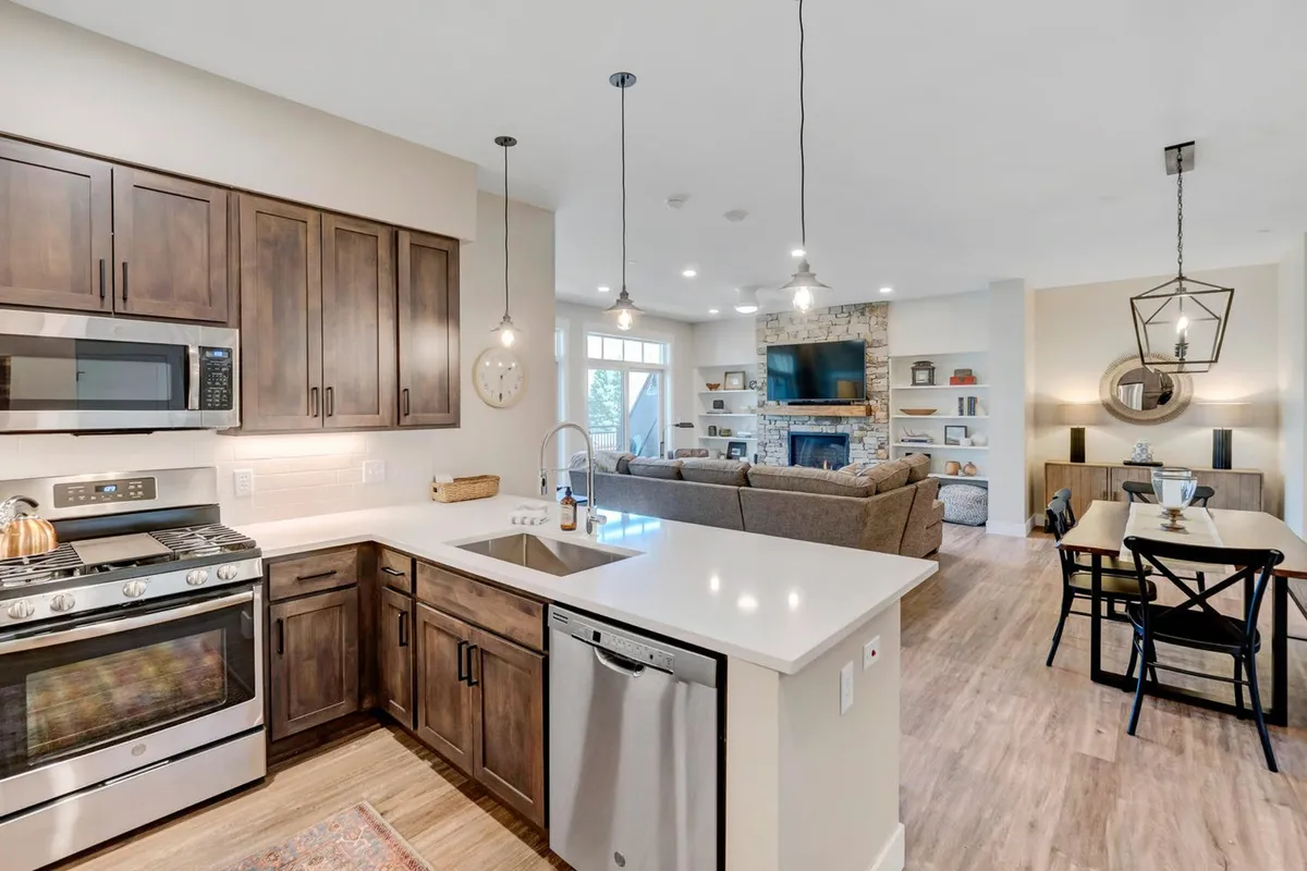 A modern kitchen with a prominent island, adjacent living area, and a dining table—ideal for cooking, entertaining, and gathering with friends or family. The space features elegant finishes and a warm, ambient light, highlighting its function as the heart of the retreat.