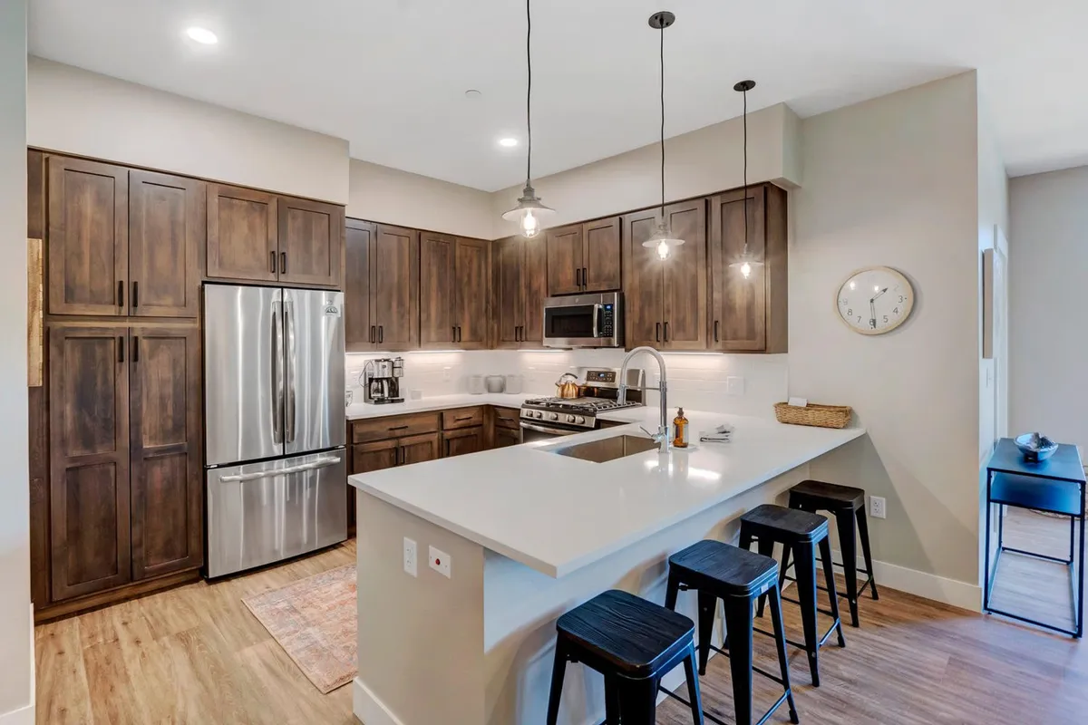 A welcoming chef’s kitchen featuring a spacious island, gleaming stainless steel appliances, rich wooden cabinetry, and stylish pendant lighting. The layout encourages both cooking and socializing, with ample workspace and an inviting atmosphere.