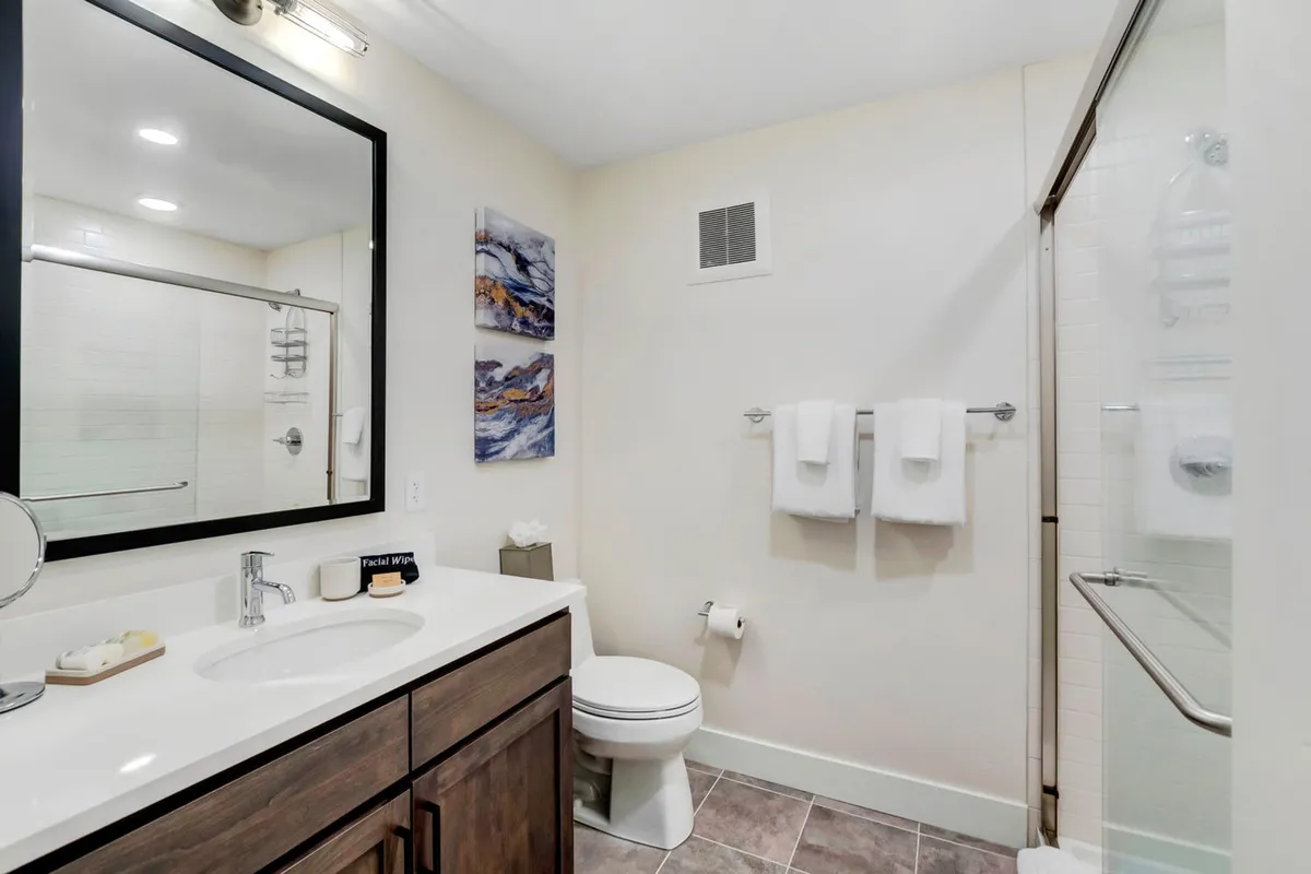A modern, spa-inspired bathroom featuring a large mirror, sleek sink, wall art, and neatly arranged towels. The space is bright, clean, and refreshing—inviting relaxation and rejuvenation after a day’s adventures.