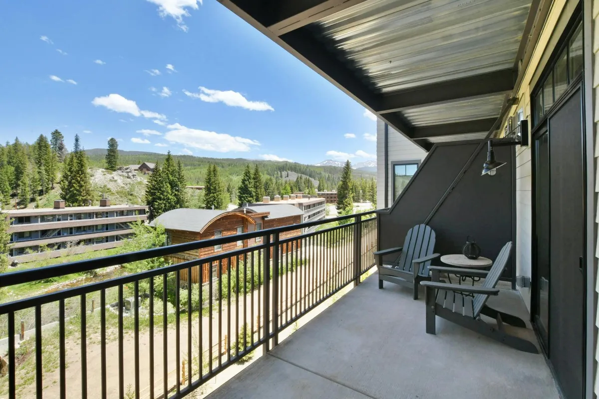 A balcony seating area overlooking mountain views and surrounded by trees, perfect for relaxed outdoor dining or morning coffee. The scene exudes tranquility and effortless indoor-outdoor flow.