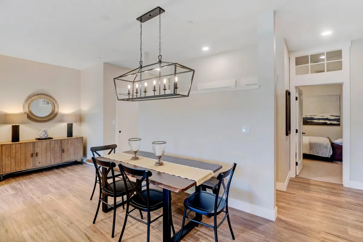 A dining area highlighted by a substantial table, elegant chandelier, and a sideboard with a large decorative mirror. The setting is warm and inviting, ideal for group meals and celebrations.